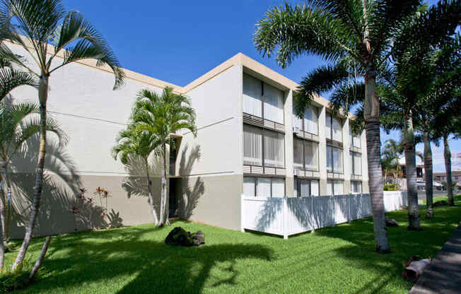 a building with palm trees in front of it at Palms of Kilani Apartments, Wahiawa, HI