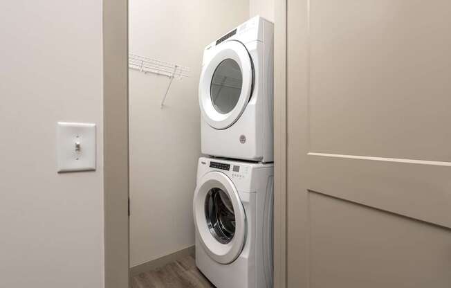 A white washing machine is stacked on top of another white washing machine in a laundry room.