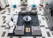 A black and white tiled floor with a coffee table and grey couches.