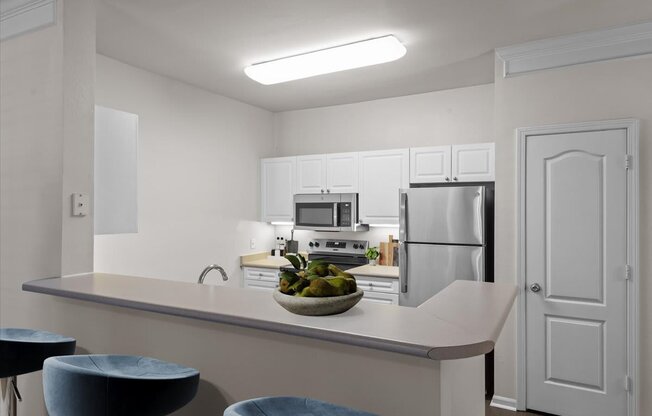 A kitchen with white cabinets and a white fridge.