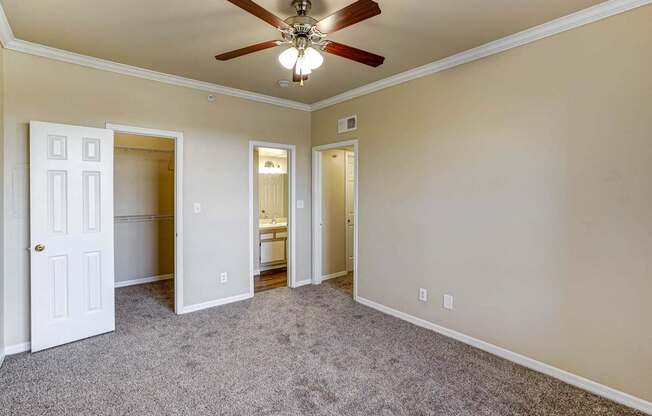 A room with a ceiling fan and carpeted floor.