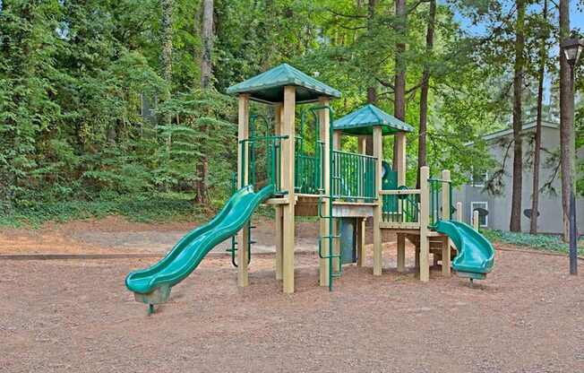 A playground with a green slide and a wooden structure. at Mill House at East Cobb, Marietta, 30067