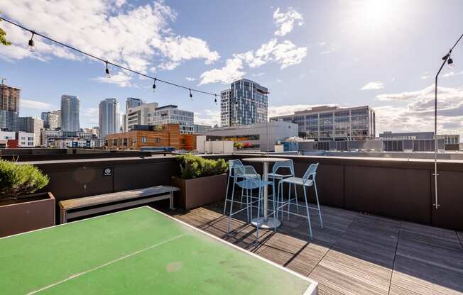 a rooftop terrace with a ping pong table and a bench with a view of the