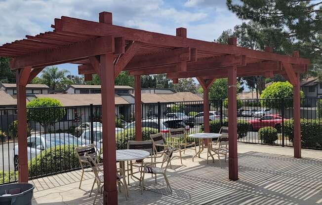 Sun deck with a wooden pergola, tables, and chairs around the pool area.