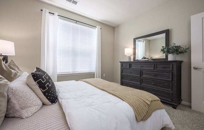 A bedroom with a bed, dresser, and mirror.