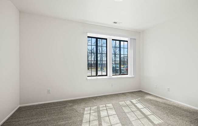 A spacious bedroom with a large window and a carpeted floor at Tanglewood Apartments, Oak Creek, WI