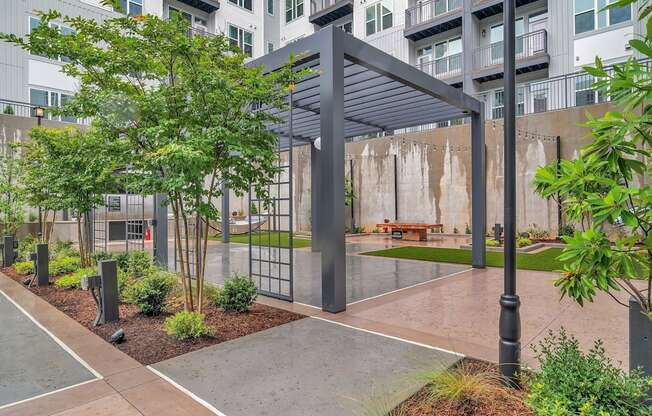 an outdoor courtyard with a bench and trees in front of an apartment building