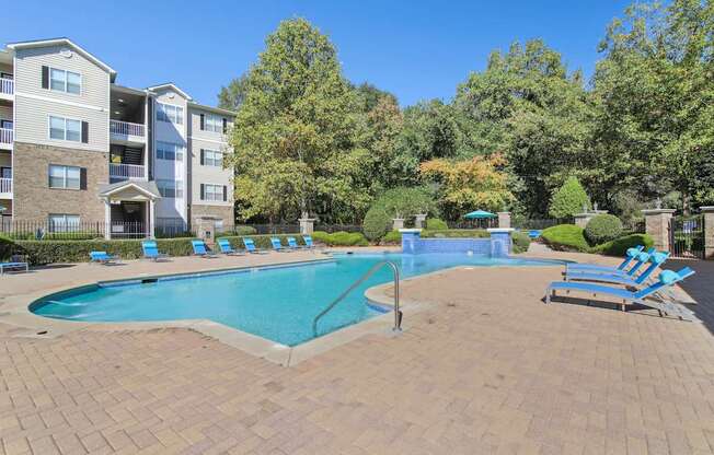 A large swimming pool surrounded by a brick patio and lounge chairs.