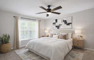 A bedroom with a large bed, a ceiling fan, and a painting on the wall.