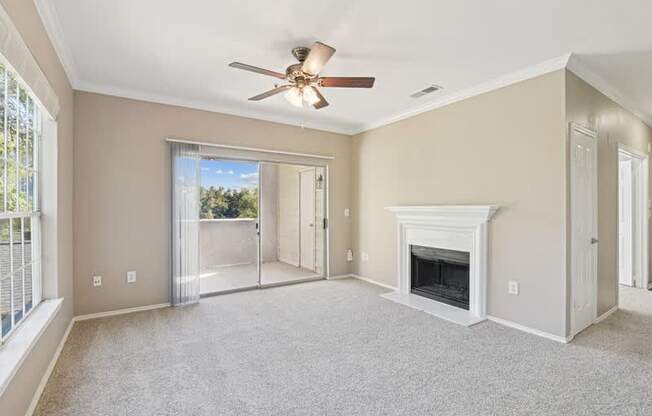 an empty living room with a fireplace and a ceiling fan