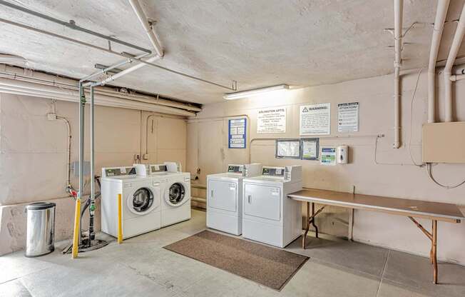 A laundry room with washers and dryers and a bench.