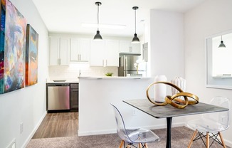 a dining area with a table and chairs and a kitchen in the background