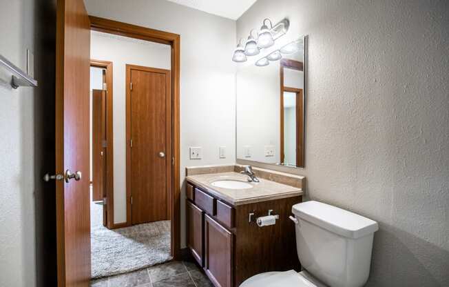 Bismarck, ND Eastbrook Apartments | A bathroom with a toilet sink and mirror