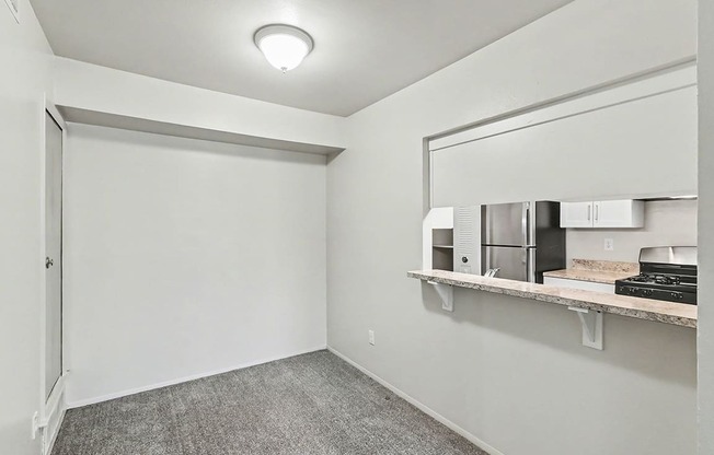 A dining room with a grey carpet and a breakfast bar at Trappers Cove Apartments, Lansing