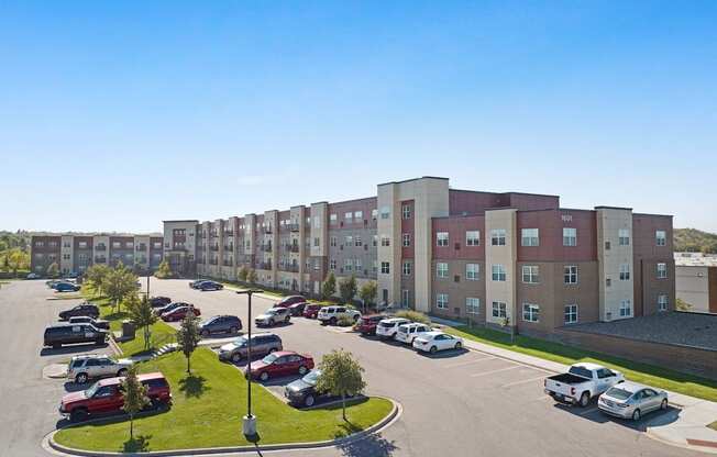 A parking lot in front of a large apartment building.