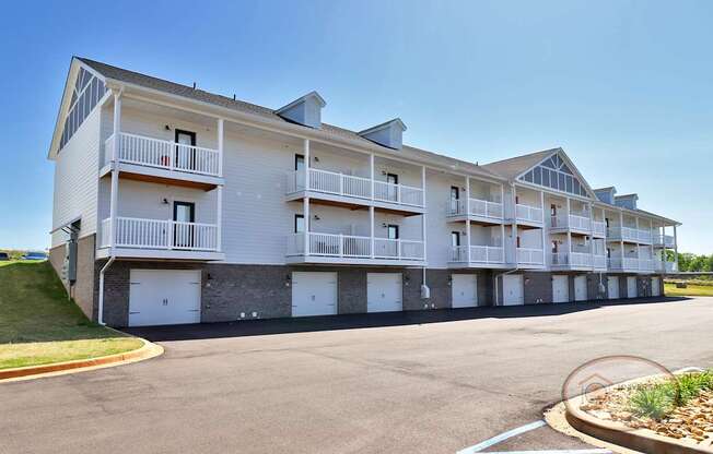 A large white apartment building with multiple balconies and garage doors.