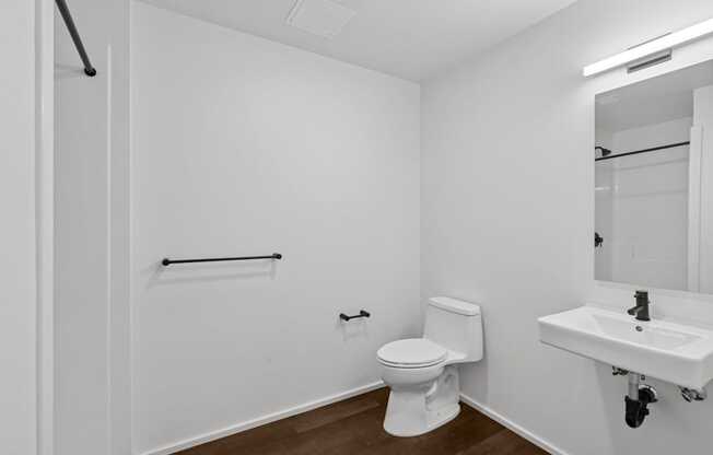 A white toilet in a small bathroom with a white sink.