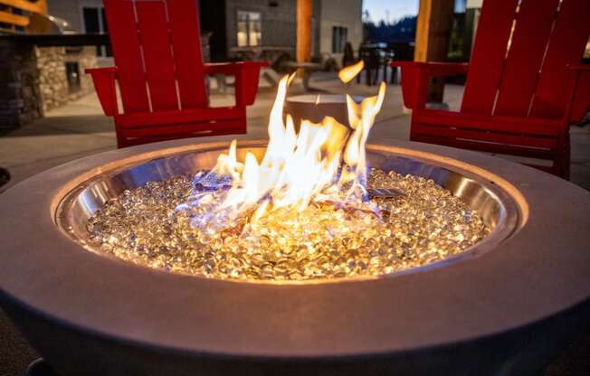 a fire pit in the middle of a patio with red chairsat Scouter's Mountain, Happy Valley Oregon