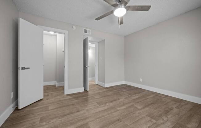 A room with a ceiling fan and wooden flooring.