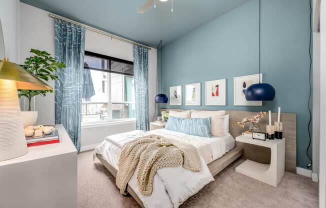 a bedroom with blue walls and a large window with blue curtains