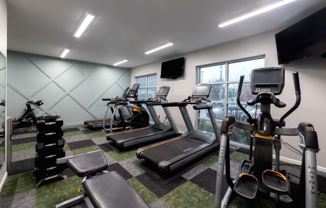 a gym with various pieces of exercise equipment and a window at 310 at Nulu Apartments-Student, Louisville Kentucky