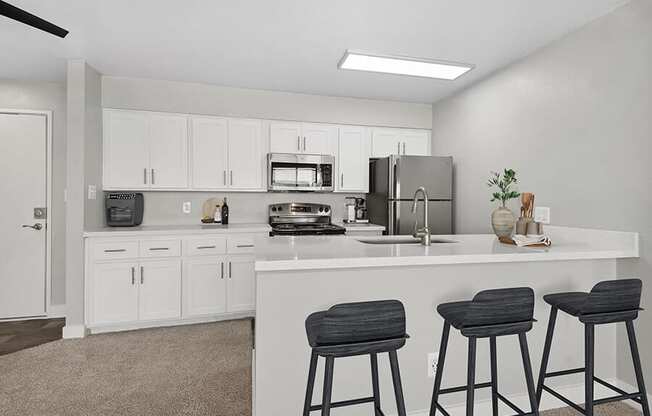 Model Kitchen with White Cabinets and Wood-Style Flooring at Crystal Creek Apartments in Phoenix, AZ.