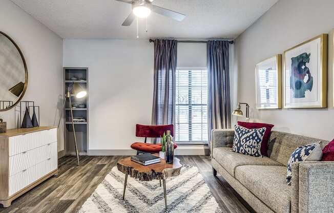 A living room with a grey couch, a red chair, and a wooden cabinet.