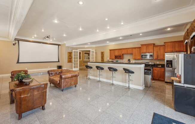 a large kitchen and living room with a bar and a projector screen