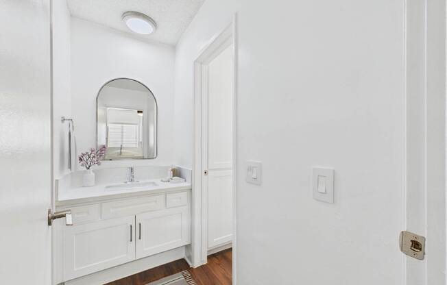 A white bathroom with a sink and mirror.