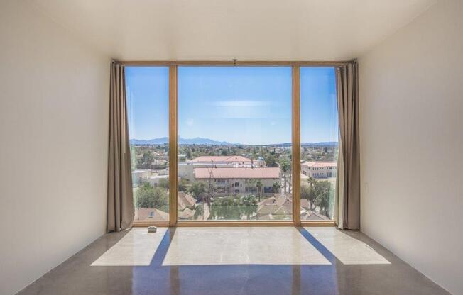 A room with a large window overlooking a residential area.
