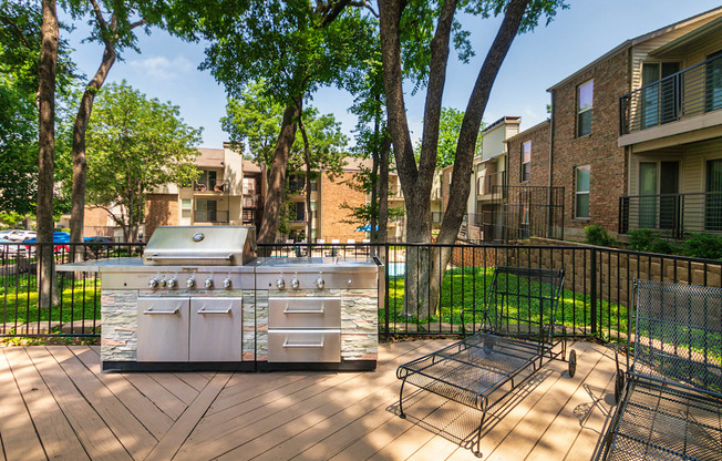 BBQ area with grill and lounge chairs at Canyon Creek Apartments in the Dallas Midtown neighborhood of Dallas, TX.