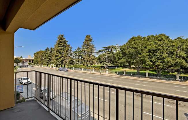 A balcony overlooks a busy street with cars and trees.