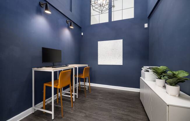 a home office with blue walls and a desk with orange chairs