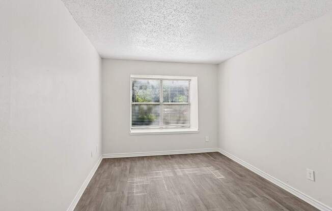 A room with a window and wooden flooring.