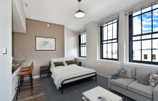 a bedroom with a bed and a couch in a room with windows at The Cosmopolitan, Minnesota, 55101