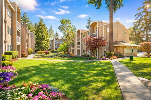 A sunny day at a well-maintained apartment complex with a walkway and flower beds.