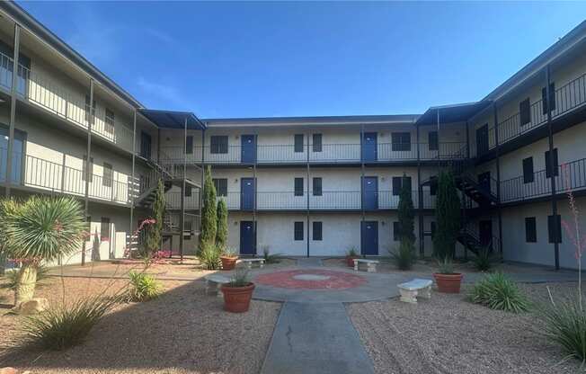 A courtyard with a red circle in the middle and plants around.