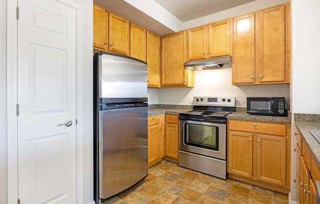 A kitchen with wooden cabinets and a stainless steel refrigerator.