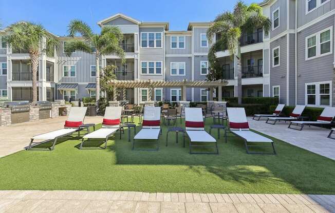 Lounge chairs arranged near palm trees by the pool at Lotus at Starkey Ranch in Odessa, Florida.