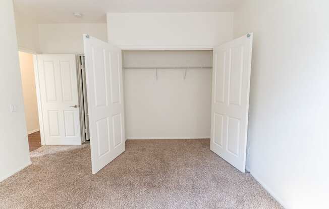 an empty bedroom with two doors leading to a walkin closet and a carpeted floor at The Vines at Riverpark, LLC, California, 93036