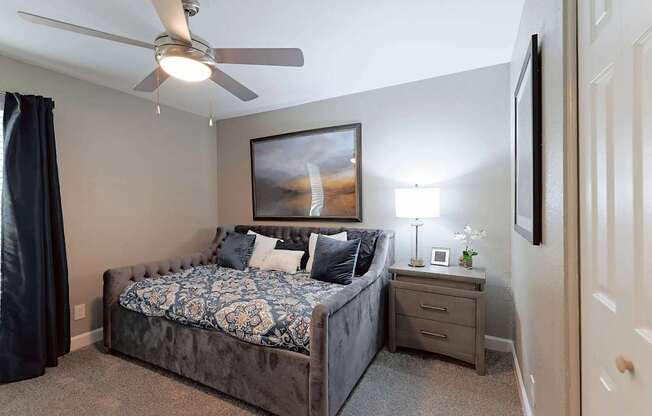 A bedroom with a bed, nightstand, and a ceiling fan.