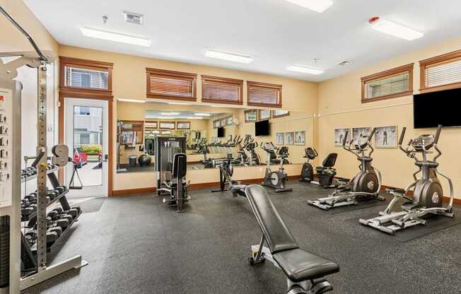 A gym with a variety of equipment including treadmills, weights, and exercise machines.