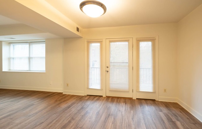 an empty living room with wood floors and french doors  at Charlesgate Apartments, Towson, MD, 21204