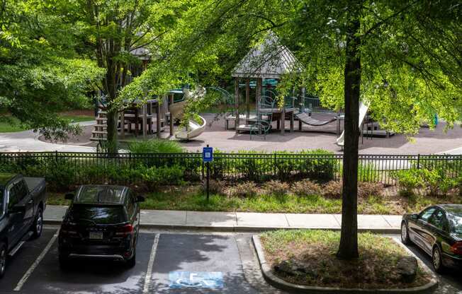 a park with a playground and cars parked in a parking lot