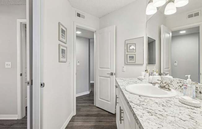 A bathroom with a marble countertop and a white sink.