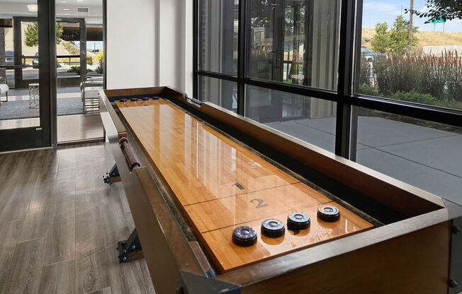 a shuffleboard table in a living room with large windows