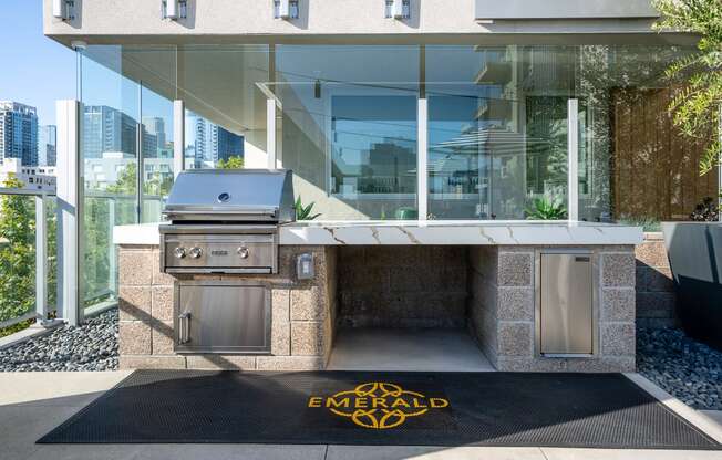 an outdoor kitchen with a propane grill and a rug with the emerald logo on it