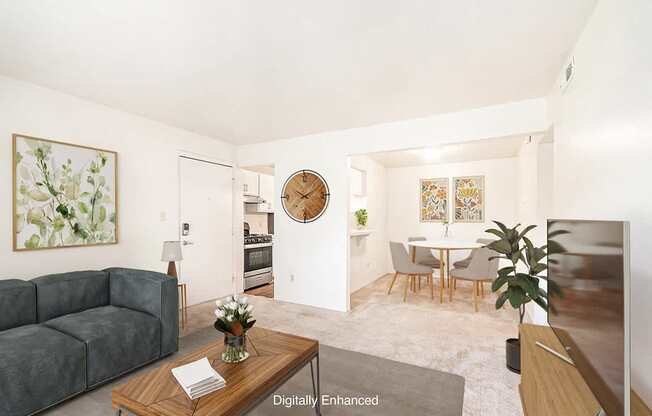 A living room with a grey couch, a wooden coffee table, and a round mirror on the wall.