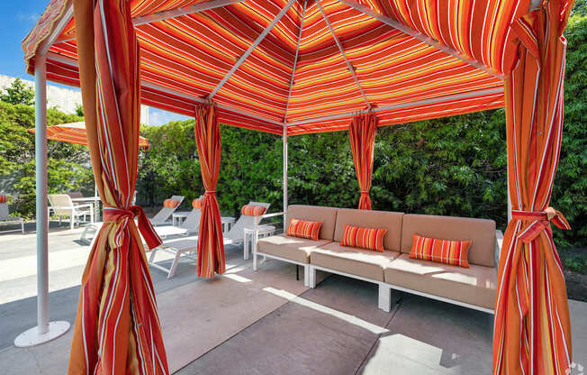 A patio with a striped canopy and a couch.