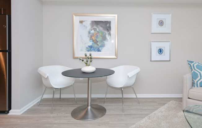 a dining room with a table and chairs and a painting on the wall at Apartments at Denver Place, Denver, CO